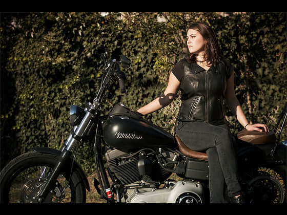  "Woman on a motorcycle, confidently wearing a leather motorcycle vest, embodying a fearless and free-spirited vibe."