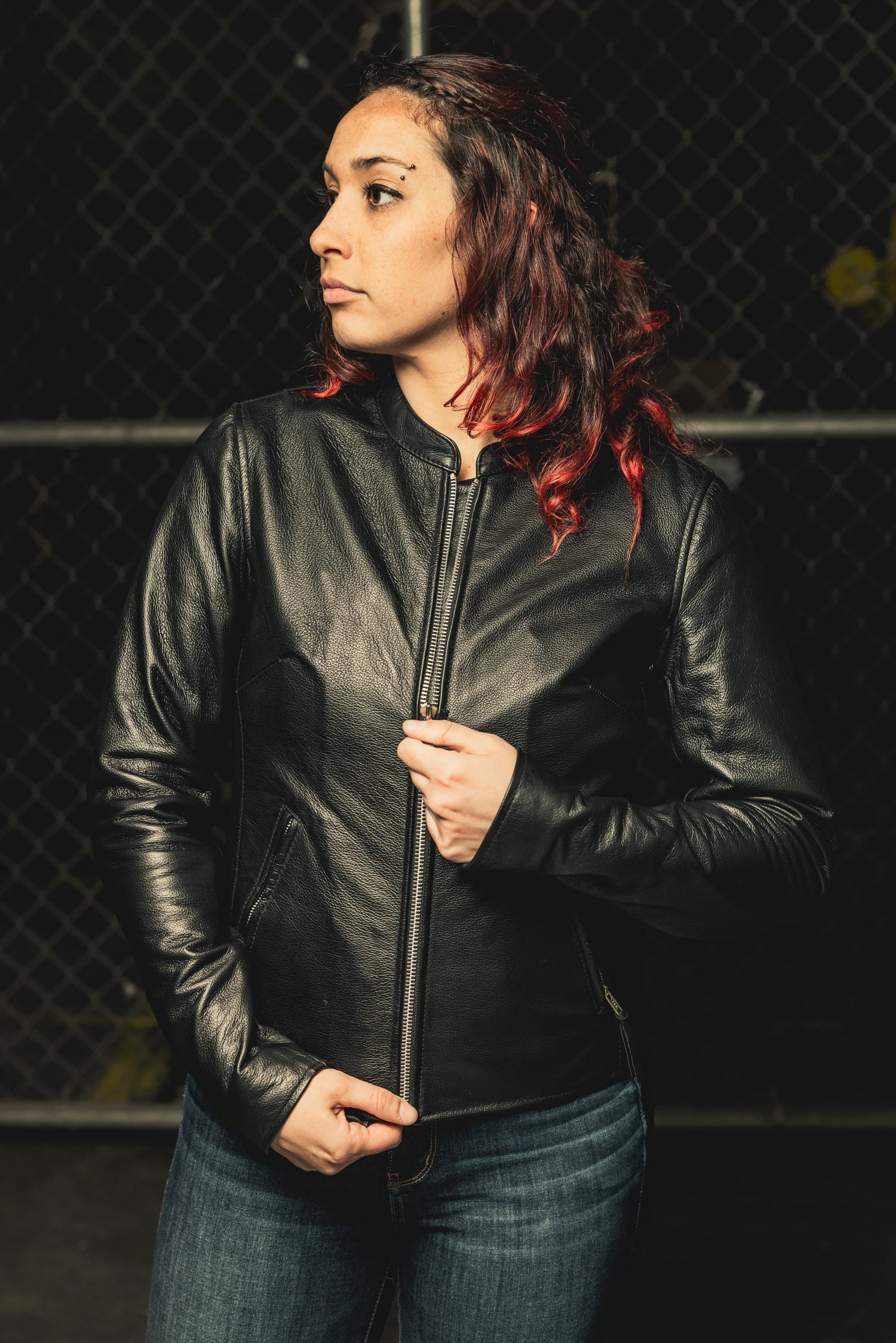  Woman wearing Flashback Leather Motorcycle Jacket, holding it closed, emphasizing the tailored fit and design.