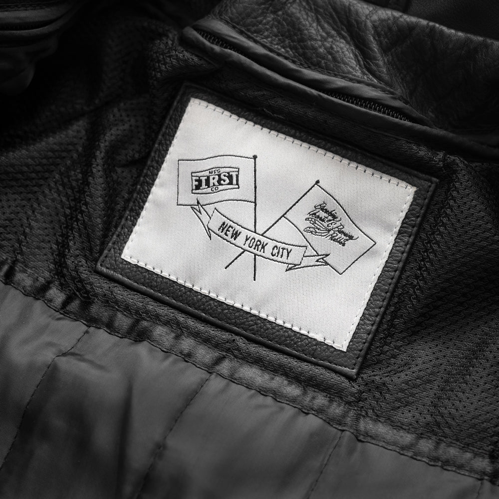 Front view of black motorcycle leather jacket, sleek and modern, with visible label.